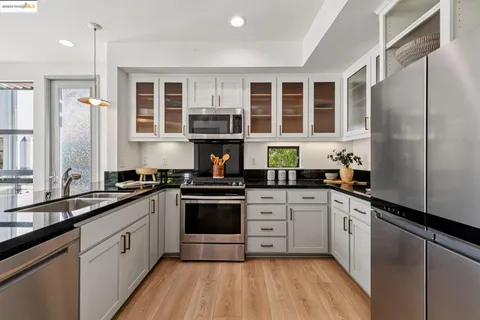 a kitchen with stainless steel appliances a sink cabinets and wooden floor