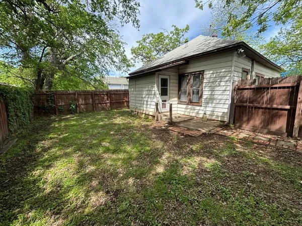 a backyard of a house with wooden fence and large trees