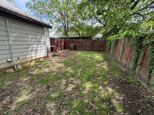 a view of a backyard with wooden fence and large trees