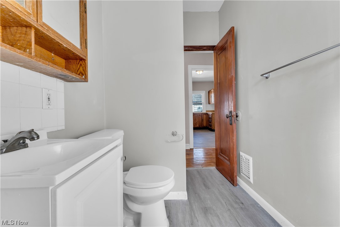 1499 Sherbrook Road South Euclid, OH 44121 - Photo 22 of 41 Bathroom featuring toilet, tasteful backsplash, oversized vanity, and hardwood floors