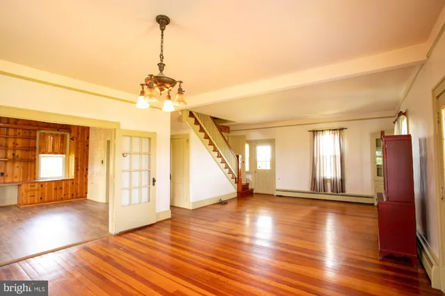 a view of a room with wooden floor chandelier and windows