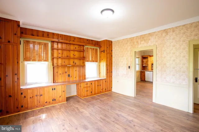 an empty room with wooden floor and windows
