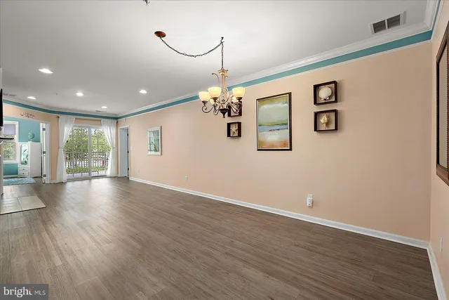 a view of a room with wooden floor chandelier and windows