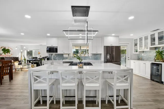 a kitchen with stainless steel appliances kitchen island granite countertop a dining table chairs and white cabinets