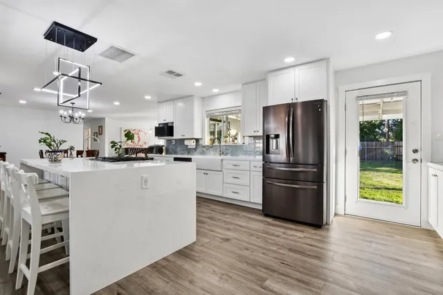 a kitchen with stainless steel appliances granite countertop a refrigerator and a stove top oven