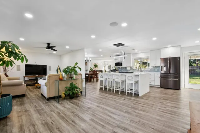 a living room with furniture kitchen view and a wooden floor