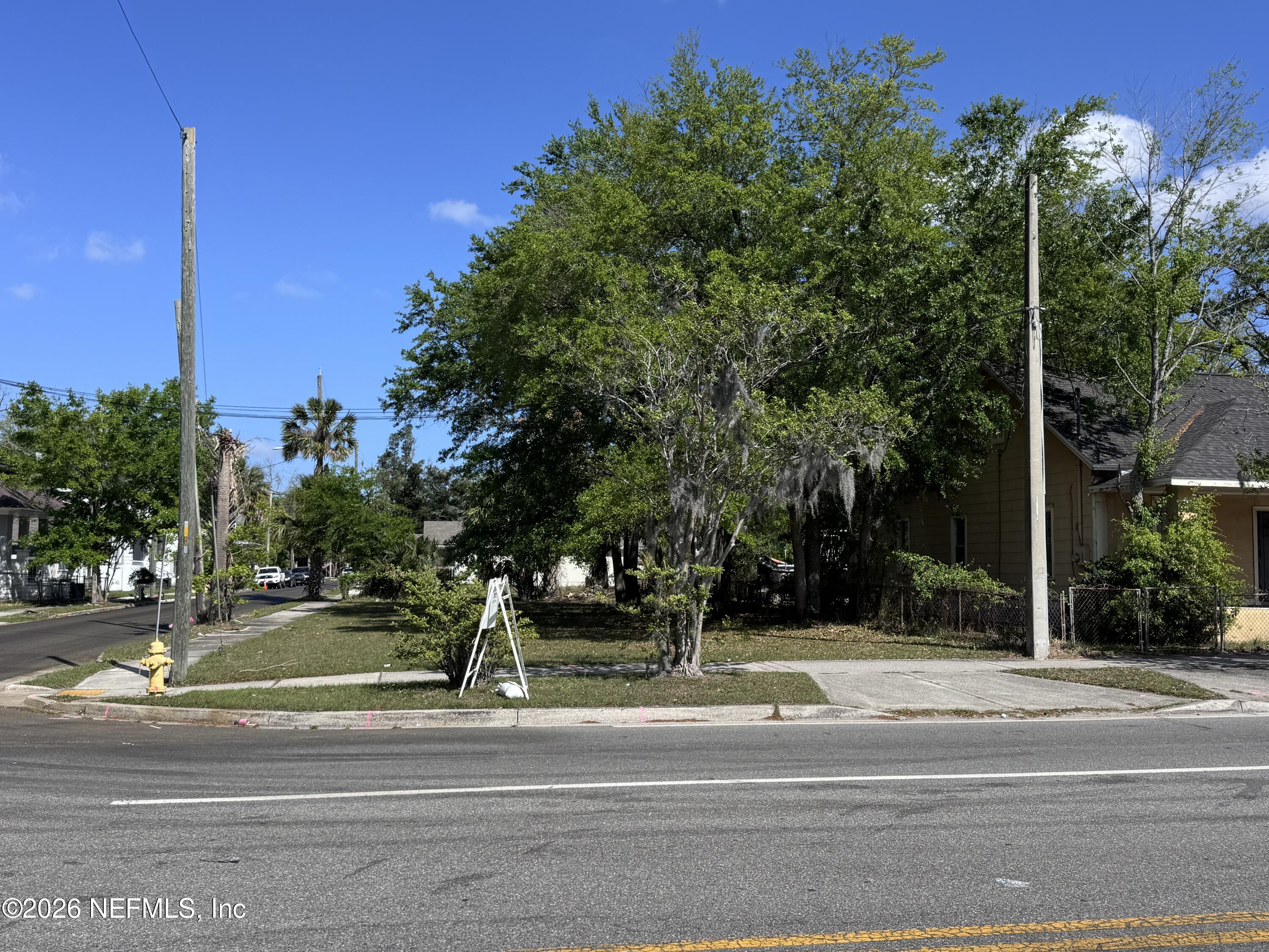 a view of a white house in a big yard with palm trees