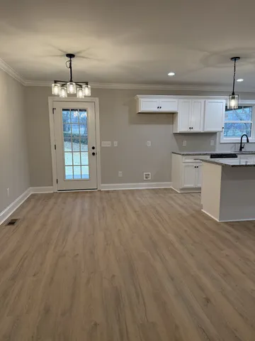 a kitchen with stainless steel appliances granite countertop a sink a stove a refrigerator and white cabinets with wooden floor