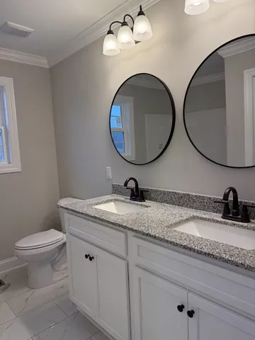 a bathroom with a granite countertop double vanity sink and a mirror