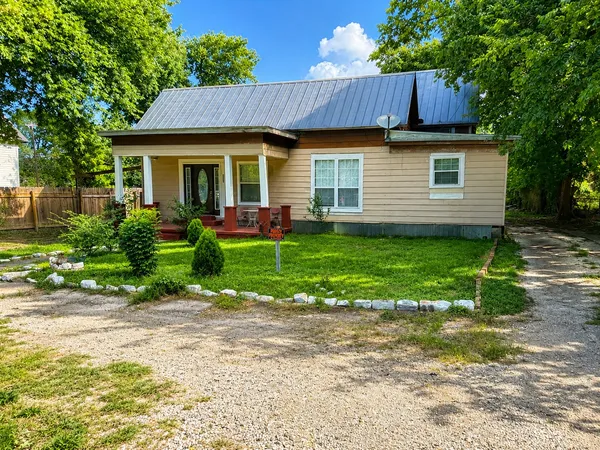 a view of a house with a yard plants and large tree