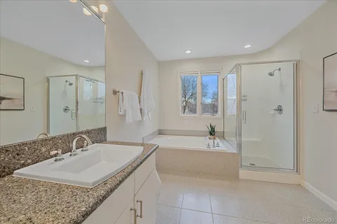 a bathroom with a granite countertop sink a mirror a bathtub and shower