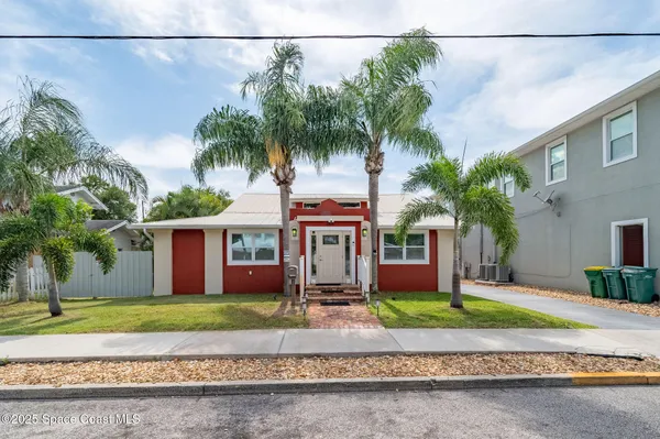 a view of a house with a yard and palm trees