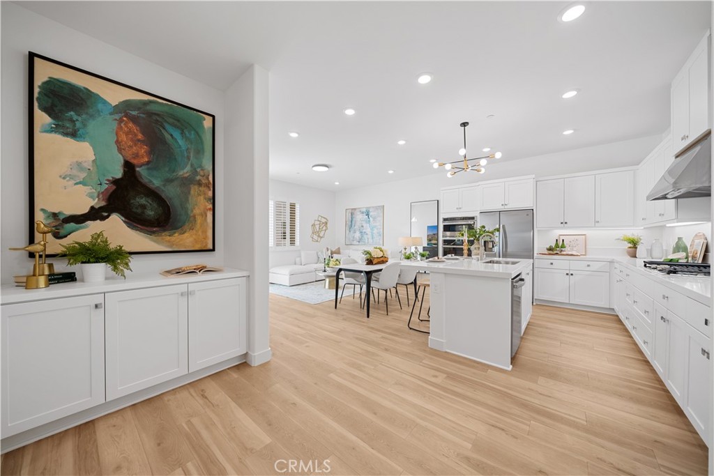 163 Baluster Irvine, CA 92618 - Photo 11 of 32 a open kitchen with white cabinets a sink and a stove with wooden floor