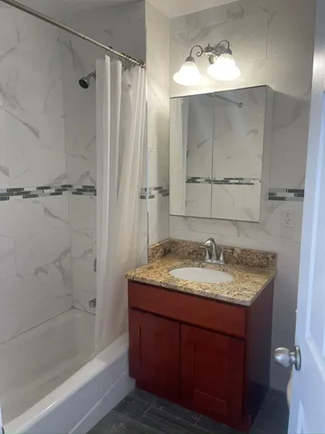 a bathroom with a granite countertop sink mirror and shower