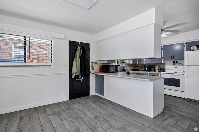 667 North 100 East Logan, UT 84321 - Photo 18 of 41 Kitchen with light countertops, white appliances, a peninsula, wood tiled floors, and ceiling fan