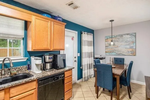 a kitchen with granite countertop a stove a sink and dining table chair