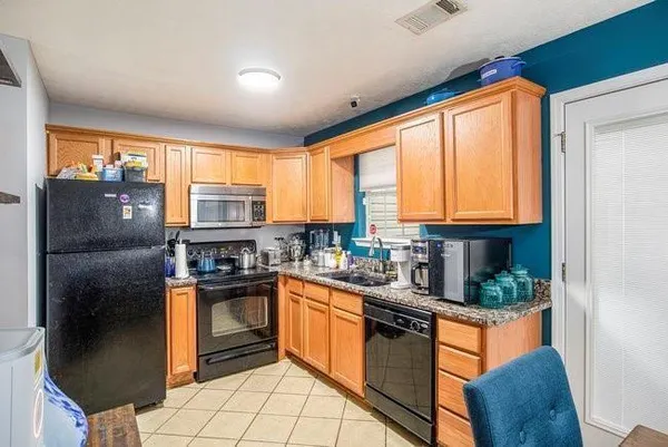 a kitchen with stainless steel appliances granite countertop a refrigerator a stove a sink dishwasher and wooden cabinets