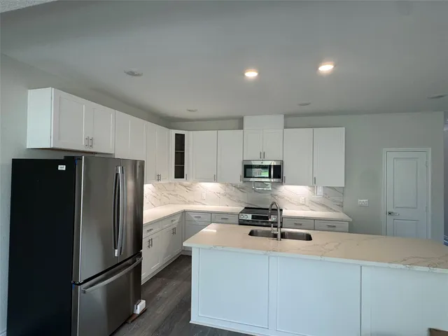 a kitchen with kitchen island a counter top space cabinets and stainless steel appliances