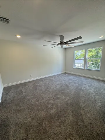 an empty room with windows and ceiling fan