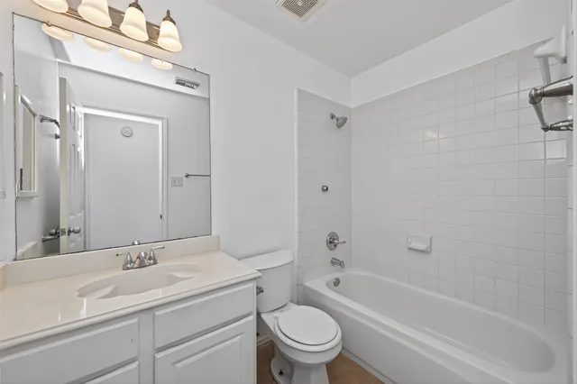 a bathroom with a bathtub shower sink vanity mirror and toilet