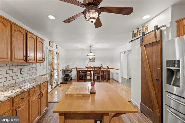 a kitchen with stainless steel appliances granite countertop a refrigerator a stove top oven a sink dishwasher and white cabinets with wooden floor