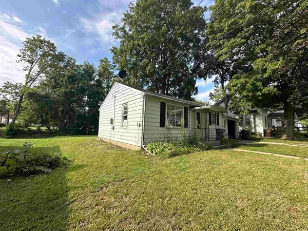 a view of a yard in front of a house with a large tree