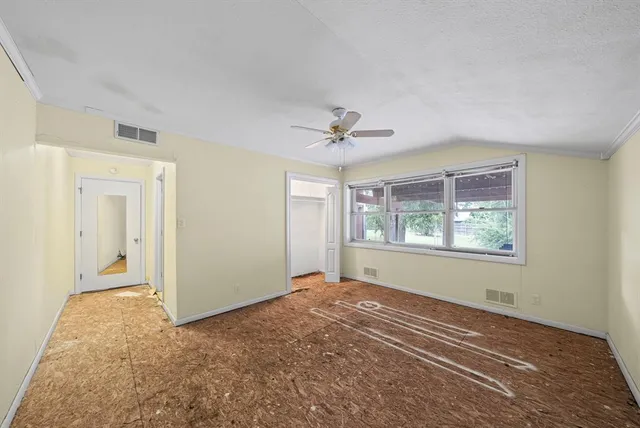 an empty room with a window and a ceiling fan