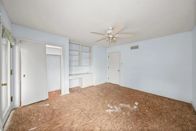 an empty room with windows and ceiling fan