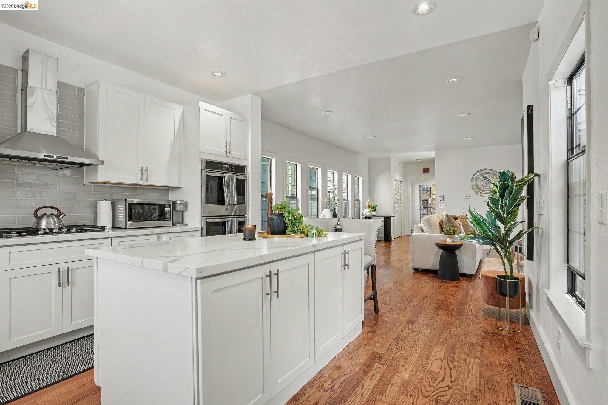 1433 Myrtle Street Oakland, CA 94607 - Photo 8 of 25 White kitchen with a large island featuring a marble-look countertop and white shaker cabinetry