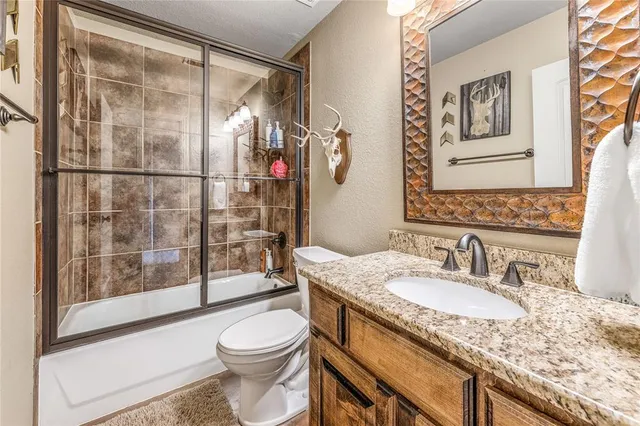 a bathroom with a granite countertop sink toilet and shower