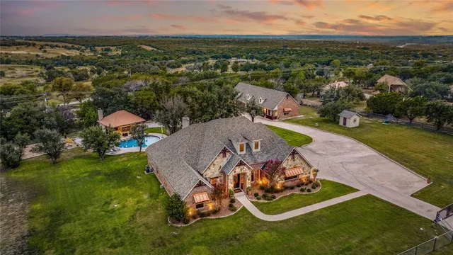 an aerial view of a residential houses with outdoor space and trees