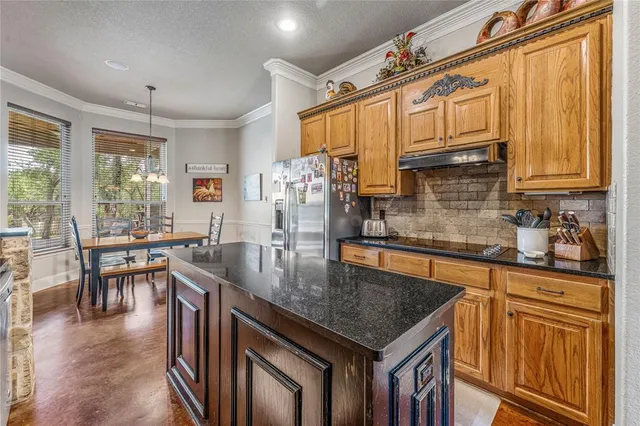 a kitchen with stainless steel appliances granite countertop a stove a refrigerator a kitchen island a dining table and chairs with wooden floor