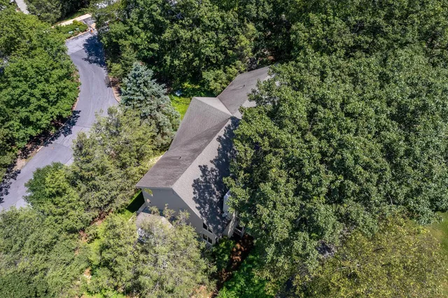 an aerial view of a house with a yard and covered with trees