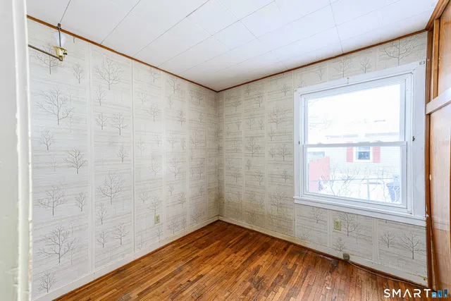 a view of an empty room with a window and wooden floor