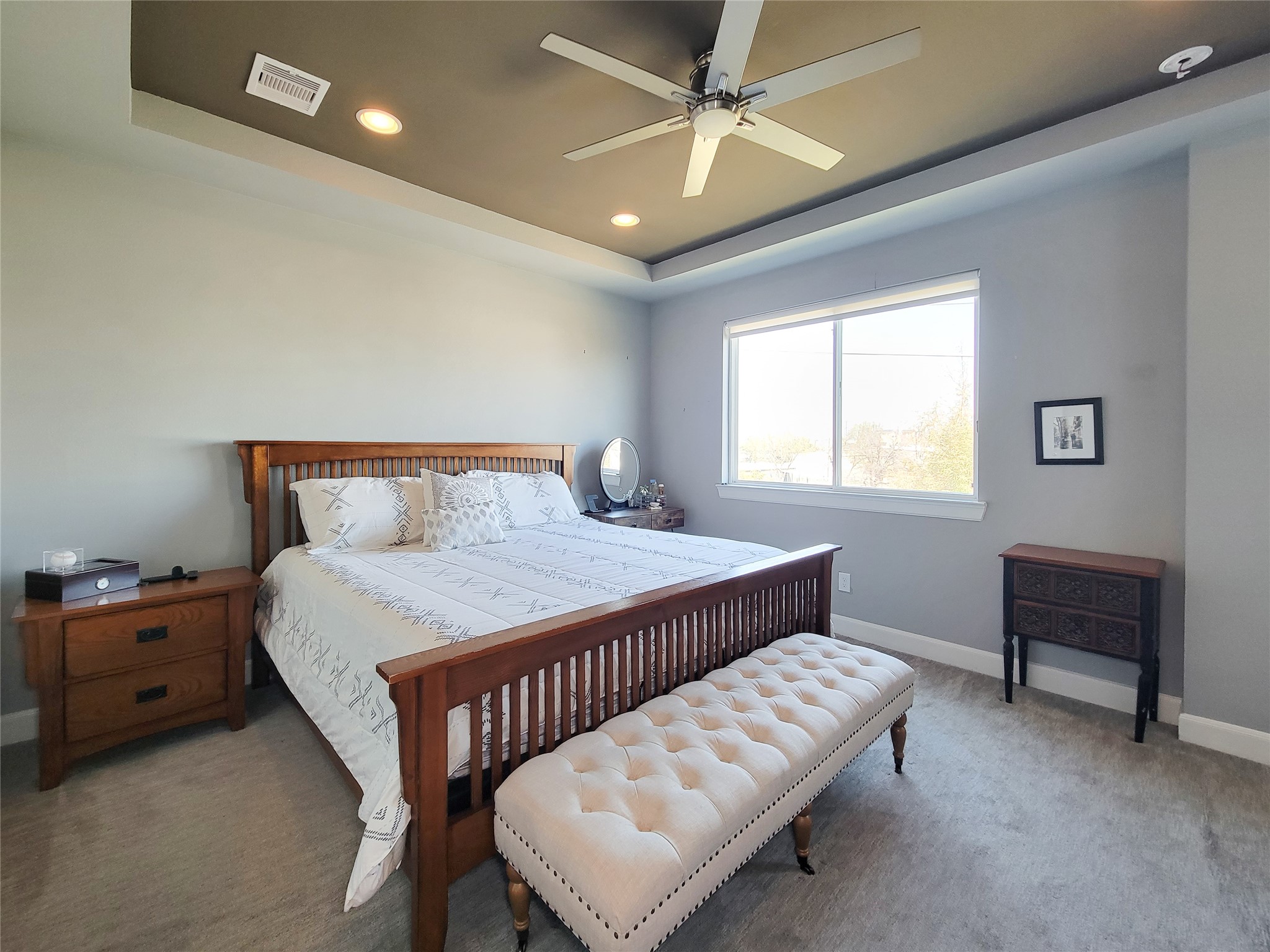 1705 Eado Point Lane Houston, TX 77003 - Photo 40 of 50 Spacious Primary bedroom with a cozy ambiance, featuring an elegant ceiling fan, ample natural light from a generous window, two walk-in closets, and an accent recessed ceiling.