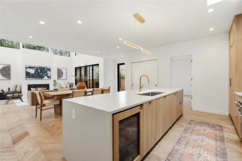 a large white kitchen with a sink and a large mirror next to a window