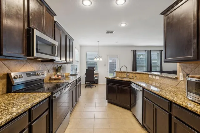 a kitchen with granite countertop stainless steel appliances a sink stove top oven and cabinets