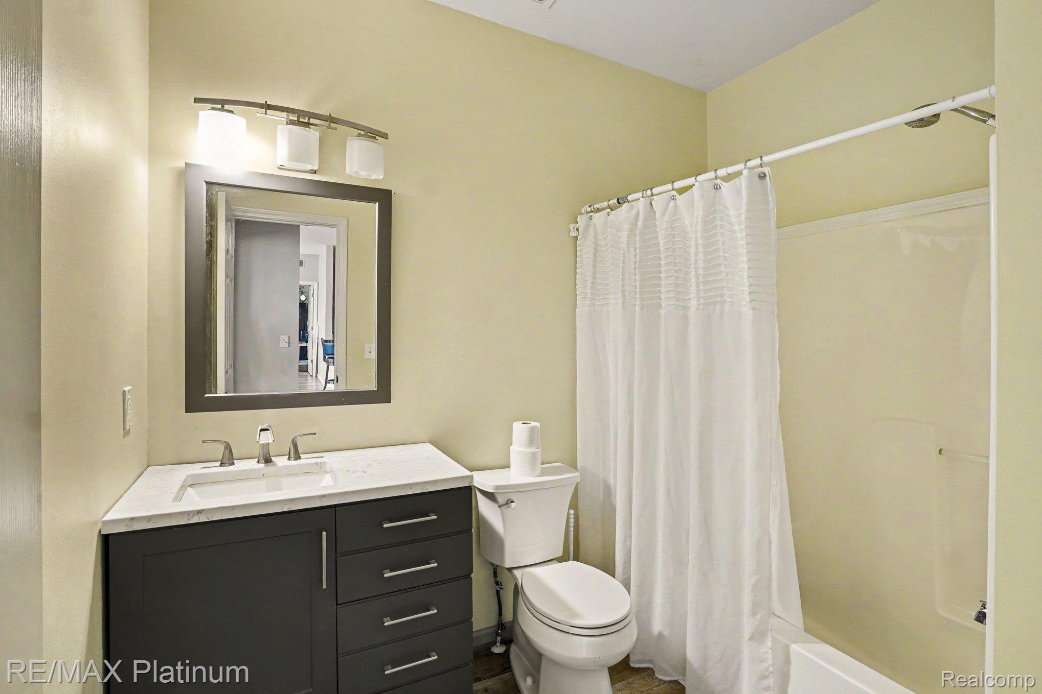 10217 Crossview Trail Howell, MI 48855 - Photo 19 of 26 Bathroom featuring a shower-tub combination, a vanity with a white countertop and rectangular sink, a framed mirror, and a three-light vanity fixture