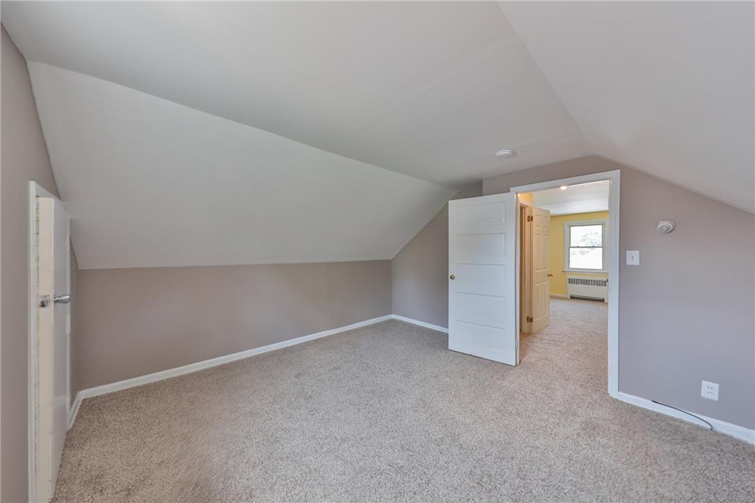 3050 Cornwall Road Bethlehem, PA 18017 - Photo 37 of 80 A well-lit bedroom features sloped ceilings and plush carpeting, with an adjacent room visible through an open doorway.