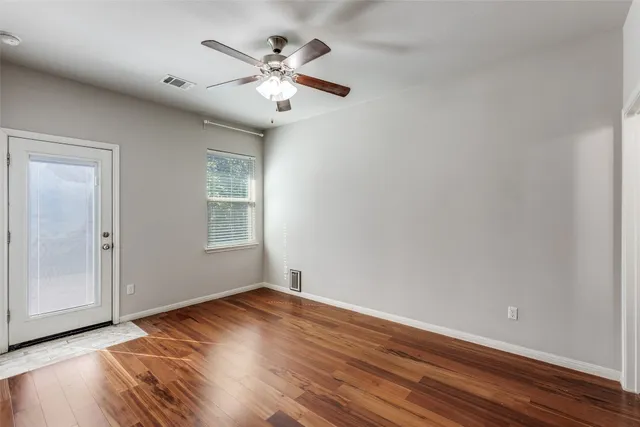 a view of an empty room with wooden floor and a window