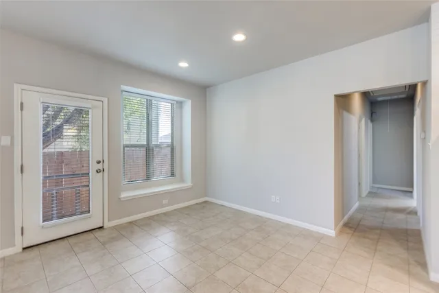 a view of an empty room with window and chandelier fan