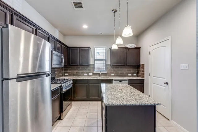 a kitchen with granite countertop stainless steel appliances a refrigerator stove top oven and sink