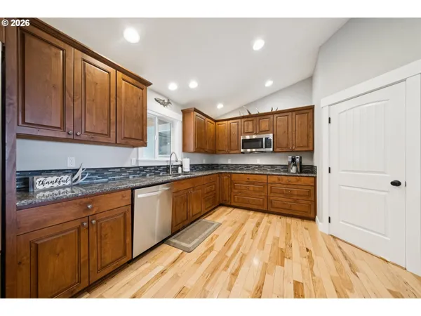 a large kitchen with stainless steel appliances kitchen island granite countertop wooden cabinets a sink and dishwasher