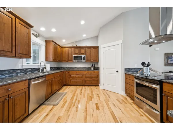 a large kitchen with cabinets wooden floor and stainless steel appliances