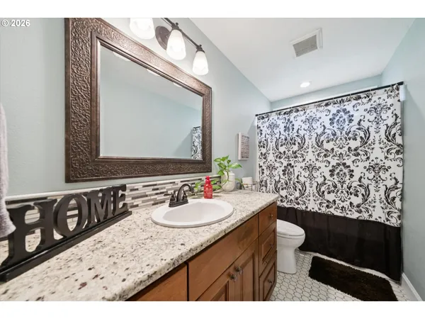 a bathroom with a granite countertop sink a toilet and a mirror