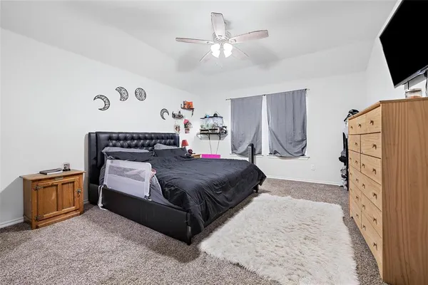 a bedroom with a bed flat screen tv and a refrigerator