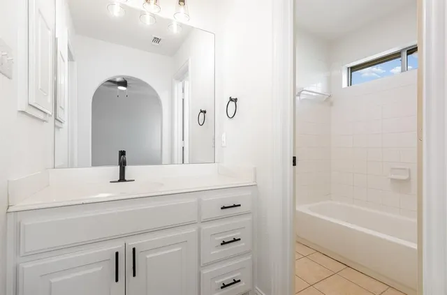 a bathroom with a bathtub sink vanity and mirror