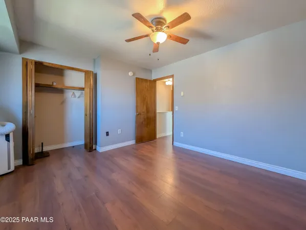 an empty room with wooden floor and a ceiling fan