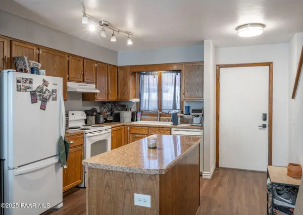 a kitchen with granite countertop a refrigerator a stove top oven a sink and dishwasher with wooden floor