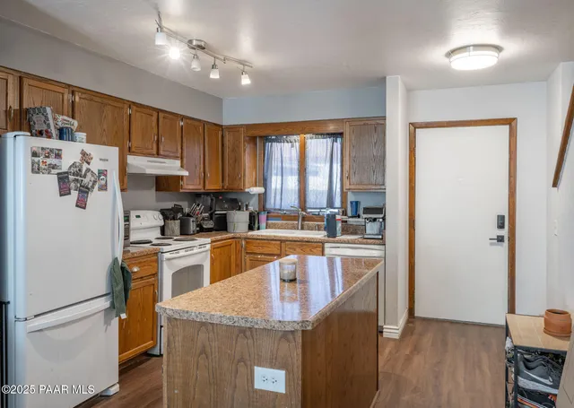 a kitchen with a refrigerator a stove top oven a sink dishwasher and white cabinets with wooden floor